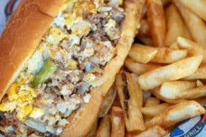Breakfast Cheesesteak sandwich with ribeye, onion, green pepper, egg, and white American cheese. Served with seasoned fries