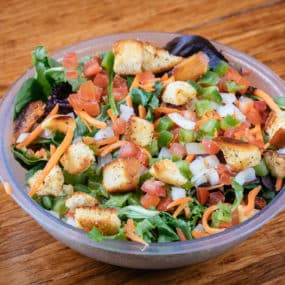 House salad catering tray with mixed greens topped with tomato, onion, green pepper, carrot, and croutons