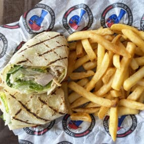 Blackened Chicken romaine lettuce and parmesan cheese inside a white tortilla with fries on The Post Sports Bar & Grill sheet paper